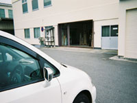 車いす利用の従業員の為の駐車場から職場への出入り口を見る。 
