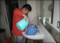 デイルームの清掃をするCさんバケツに洗剤を量りいれ、決められた手順で椅子を拭いていく