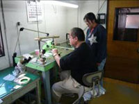 取締役の吉田課長(身体障害者)が知的障害者の女性にマンツーマンで部品製造を指導